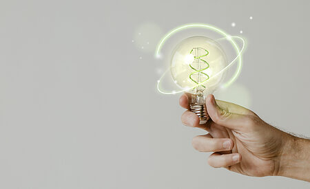Green energy with hand holding an environmental light bulb background